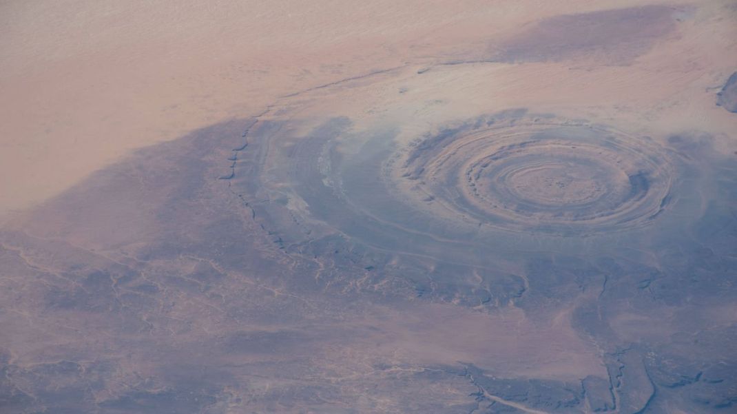 Ein Foto der mysteriösen Richat-Struktur aus dem All: Das riesige, ringförmige "Auge der Sahara" erinnert an einen Krater und ist von symmetrischen, runden, wenige Meter hohen Gesteins-Wällen umgeben. 