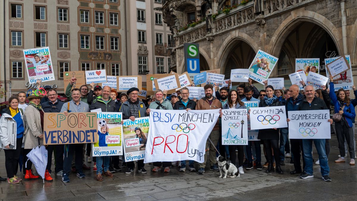 Mehrere Menschen nehmen an einer Demonstration auf dem Münchner Marienplatz für die geplante Olympia-Bewerbung Münchens teil und halten Plakate.