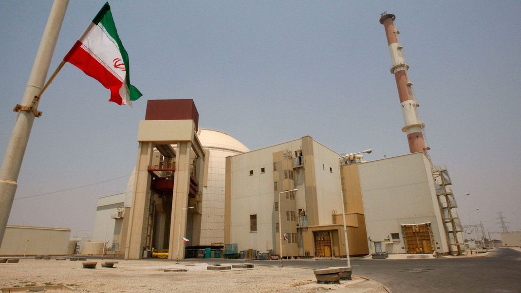 21.08.2010, Iran, Bushehr: Eine iranische Flagge flattert vor dem Reaktorgebäude des Kernkraftwerks Buscher.