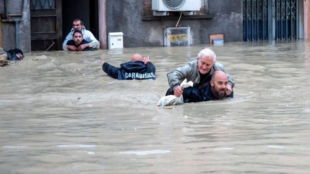 Schwere Unwetter in Italien: Carabinieri retten Einwohner und schleppen sie durch die Fluten. Zahlreiche Menschen sind bereits ums Leben gekommen.