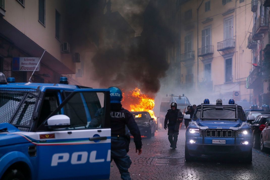 Vermummte Hooligans haben vor dem Spiel auf einer Straße ein Polizeiauto in Brand gesetzt. 