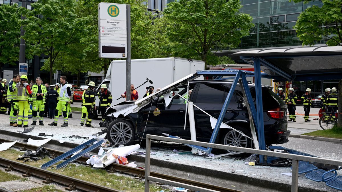 Einsatzkräfte stehen bei dem Unfallfahrzeug und einer zerstörten Haltestelle.