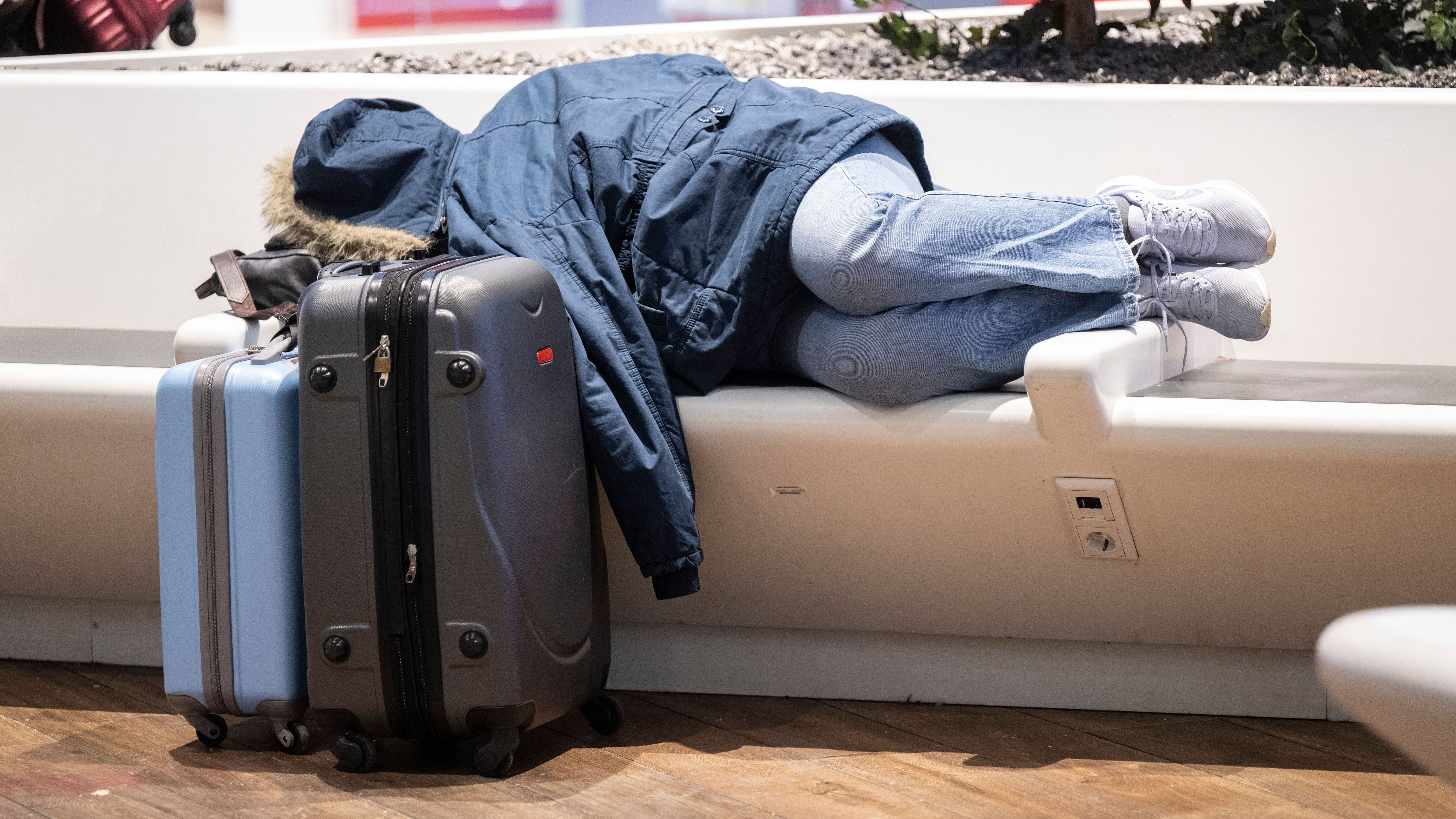 Ganz Deutschland steht still: Ein gestrandeter Fluggast schläft auf einer Bank am Flughafen Frankfurt.