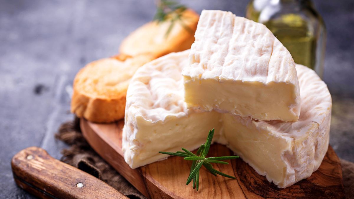 Camembert cheese with rosemary on wooden board