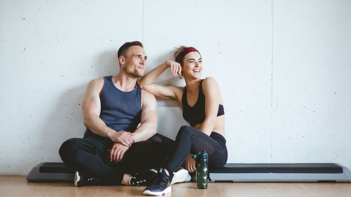 Athlete couple smiling after good workout in gym. Sporty Gym Concept