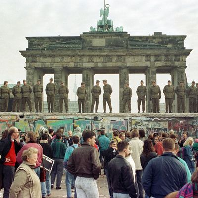 Ostberliner Grenzsoldaten stehen auf der Berliner Mauer vor dem Brandenburger Tor