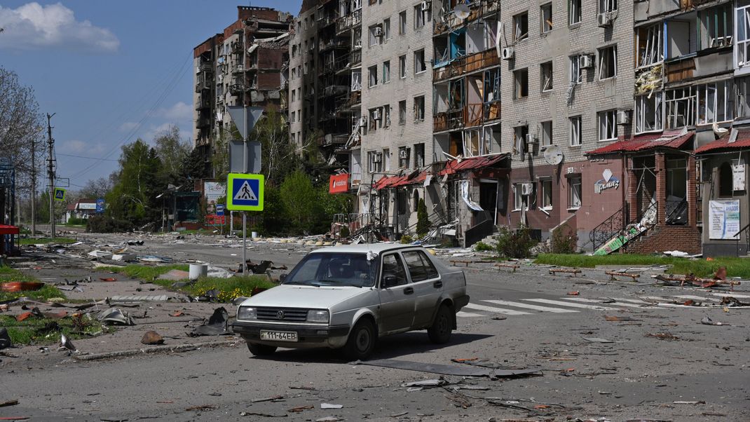 Ein verlassenes Auto steht vor dem Hintergrund beschädigter Gebäude im Zentrum von Pokrowsk, dem Schauplatz der schwersten Gefechte mit den russischen Truppen in der Region Donezk.