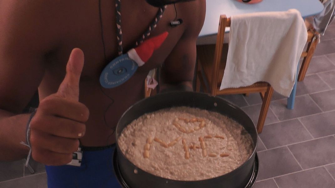 Christian schreibt auf seinen Kuchen die Initialen von ihm und Maja.