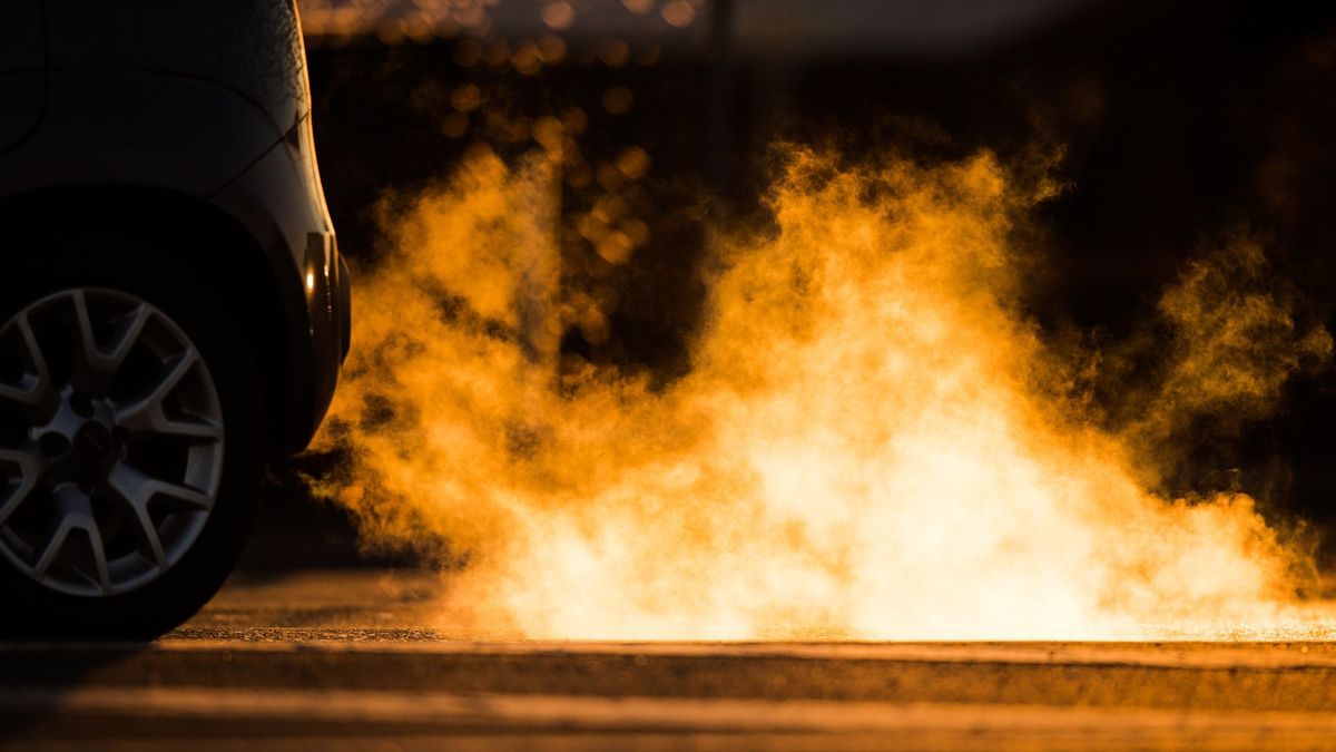 Abgase kommen im Gegenlicht der aufgehenden Sonne aus dem Auspuff eines Autos.