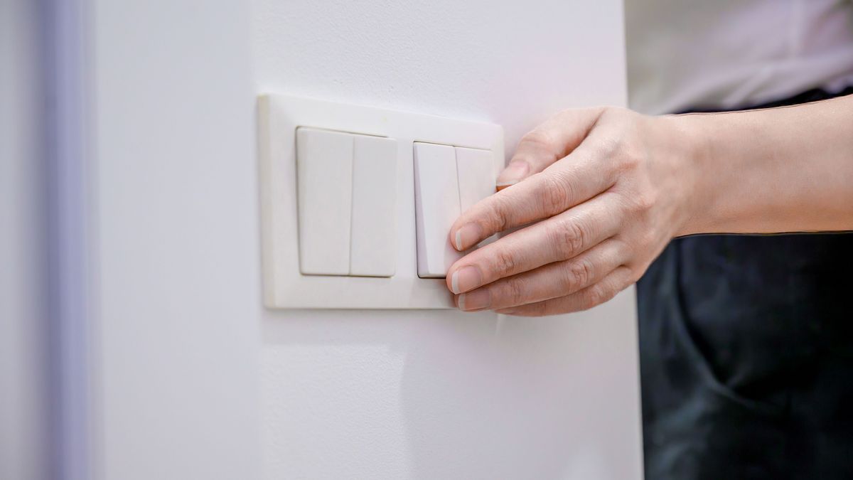 A woman turns off the home light switch when she leaves the room. Power, energy saving, energy saving.