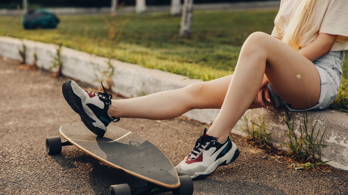 Teenage girl legs with a long board. Legs cropped.