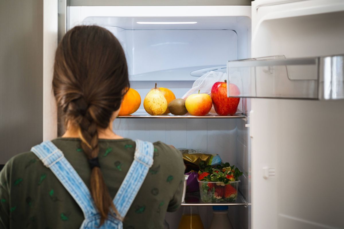 Frau vor Kühlschrank mit Obst und Gemüse