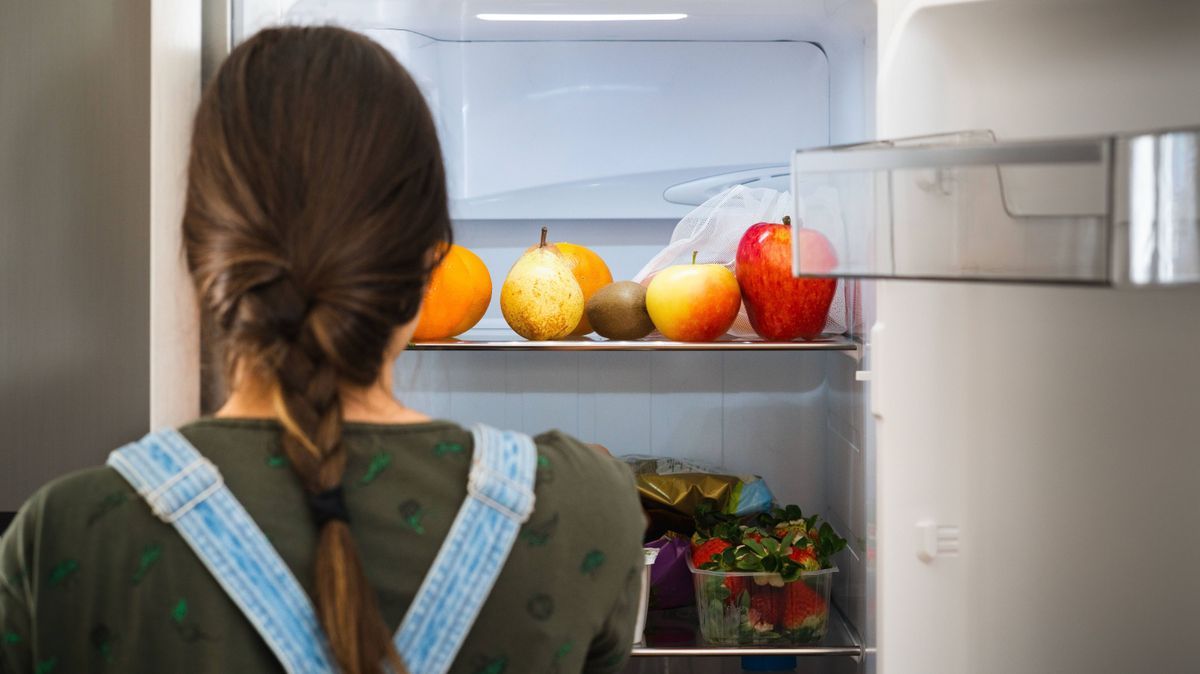 Frau vor Kühlschrank mit Obst und Gemüse