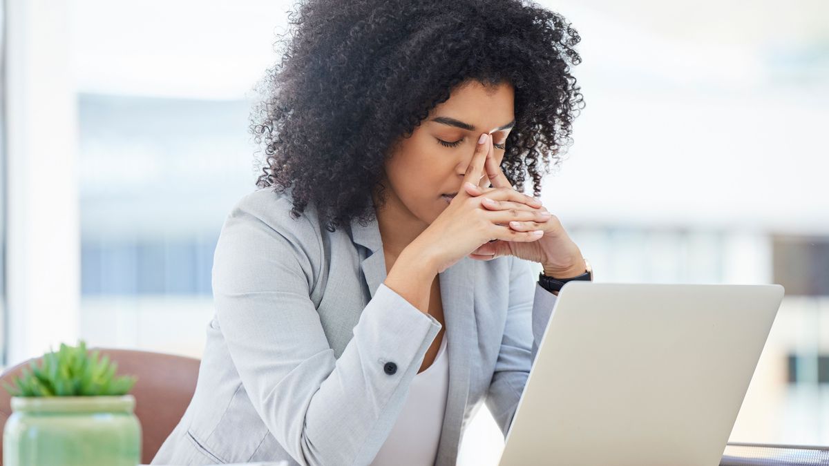 Stress, anxiety and burnout with a business black woman at work using a laptop while suffering from a headache. Compliance, computer and mental health with a female employee struggling on a deadline