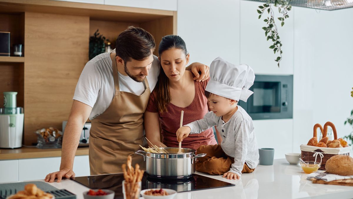 Young family cooks spaghetti while making lunch in kitchen. 