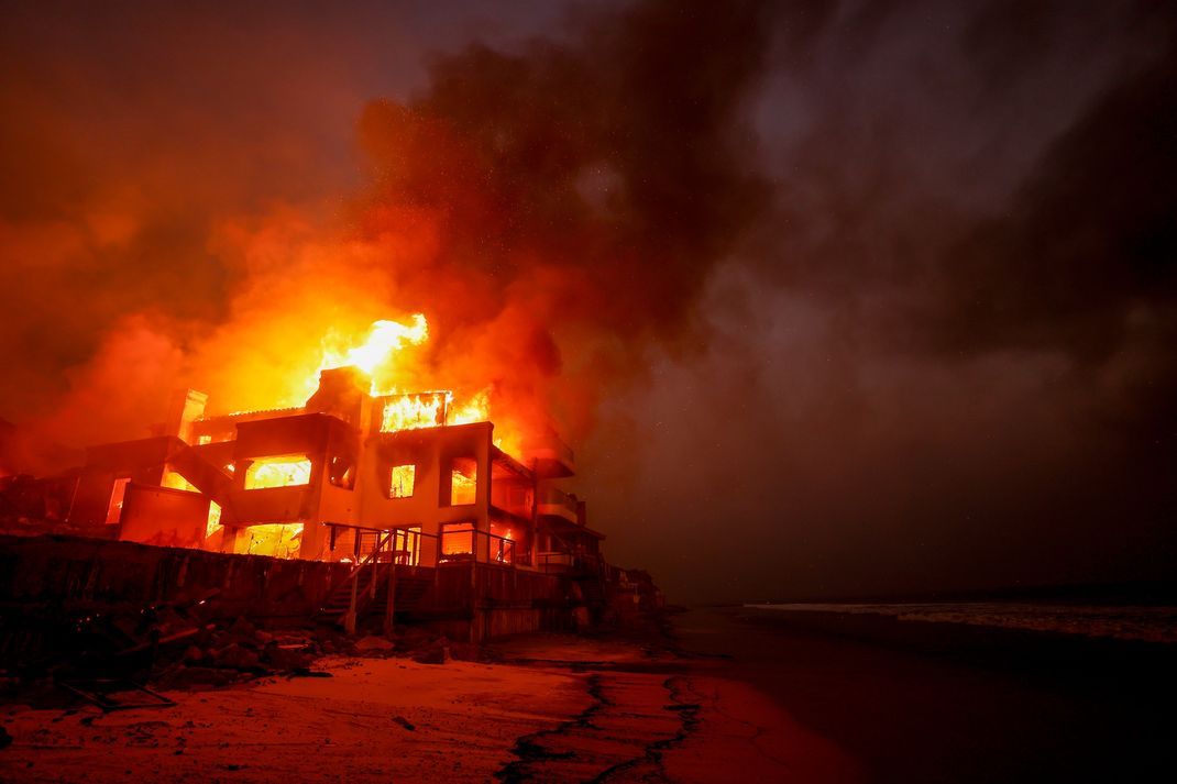 Das Palisades-Feuer brennt auf einem Grundstück am Strand.