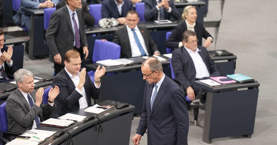 Friedrich Merz, CDU-Bundesvorsitzender und CDU/CSU-Fraktionsvorsitzender im Bundestag, läuft an der AfD-Fraktion (r) vorbei, die nach der Bekanntgabe der Ergebnisse der Abstimmung für eine Verschärfung der Migrationspolitik reagiert.