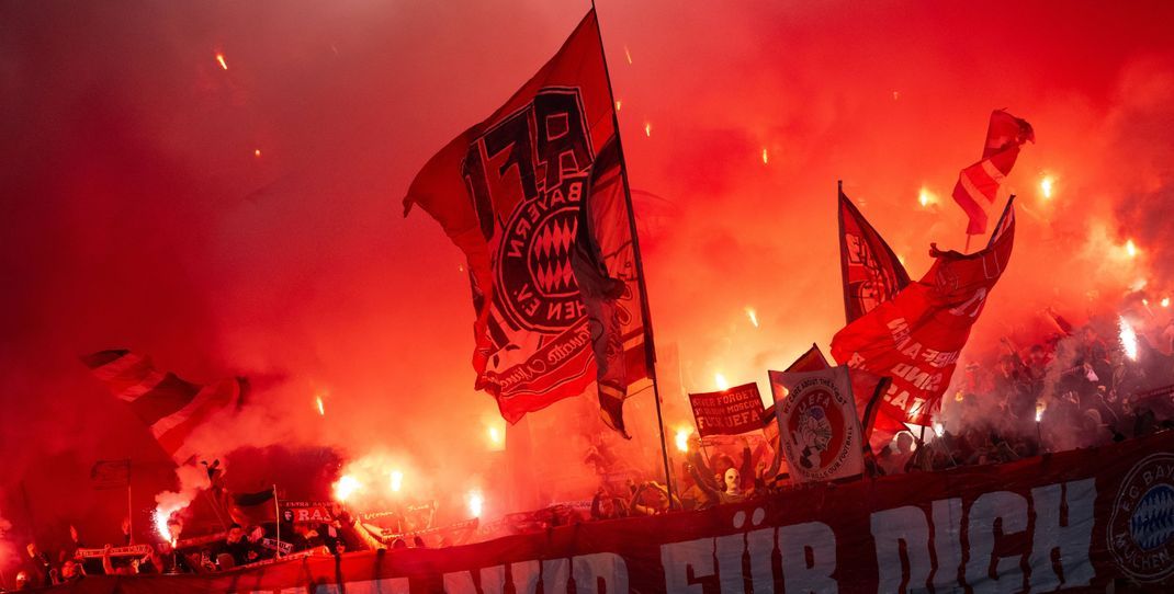 Fans von Bayern München schwenken Fahnen und brennen Pyrotechnik ab.  Der FC Bayern ist wegen Fehlverhaltens seiner Fans in der Champions League hart bestraft worden. 