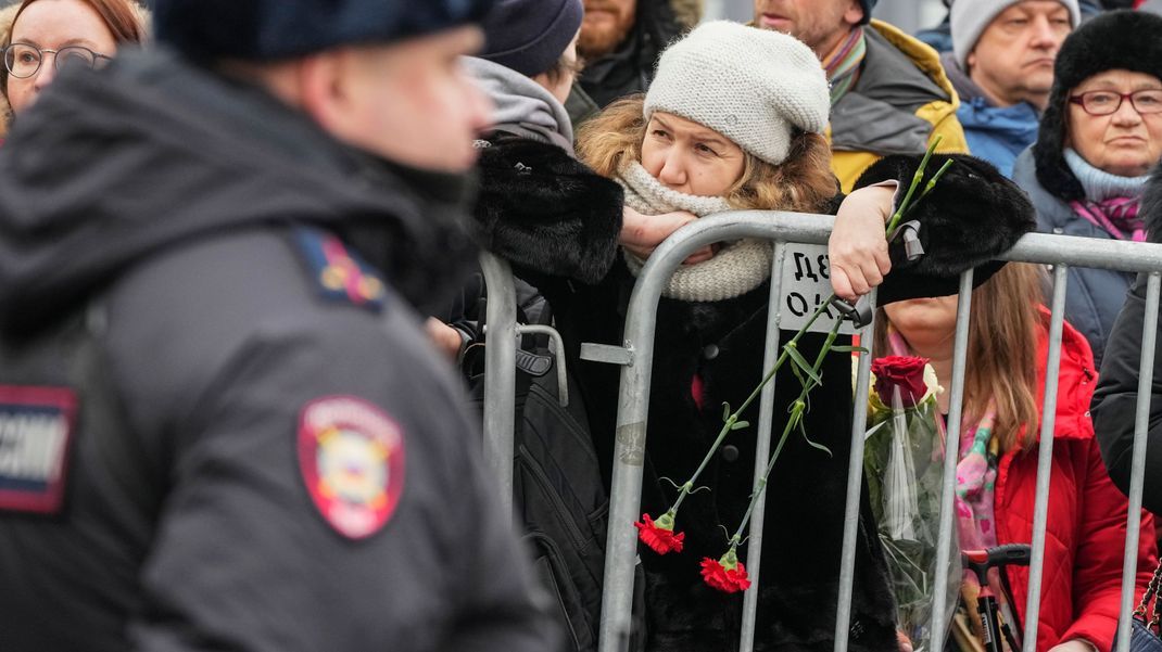 Ein Polizist bewacht Zaungäste in der Nähe der Kirche zu Ehren der Gottesmutterikone "Lindere meine Trauer" im südöstlichen Bezirk Marjino, in der Kremlgegner Alexej Nawalny beigesetzt werden soll. 