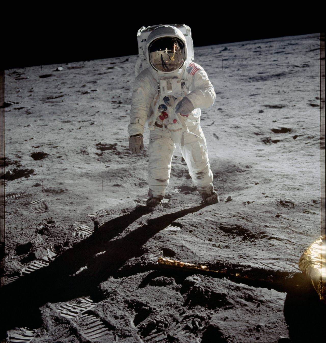 Buzz Aldrin auf dem Mond, fotografiert von Neil Armstrong. Im Helm spiegelt sich die Mondlandefähre, im Vordergrund sind Fußspuren zu sehen.