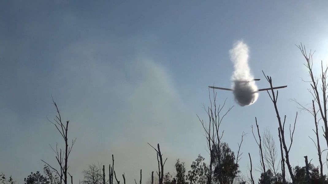 Ein Löschflugzeug wirft Wasser ab über einem Waldbrand in einem munitionsbelasteten Gebiet bei Jüterbog.