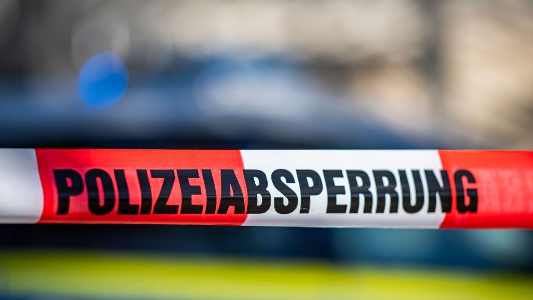 Ein Absperrband mit der Aufschrift «Polizeiabsperrung» ist vor einem Polizeiwagen aufgespannt.