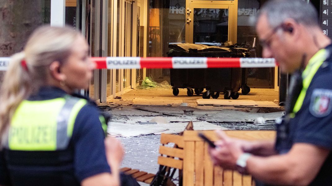 Polizeibeamte stehen nach einer Explosion vor einem beschädigten Gebäude in der Innenstadt am Hohenzollernring.