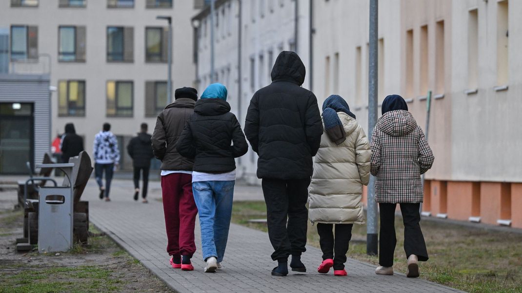 Migranten gehen über das Gelände der Zentralen Erstaufnahmeeinrichtung für Asylbewerber (ZABH) des Landes Brandenburg in Eisenhüttenstadt.

