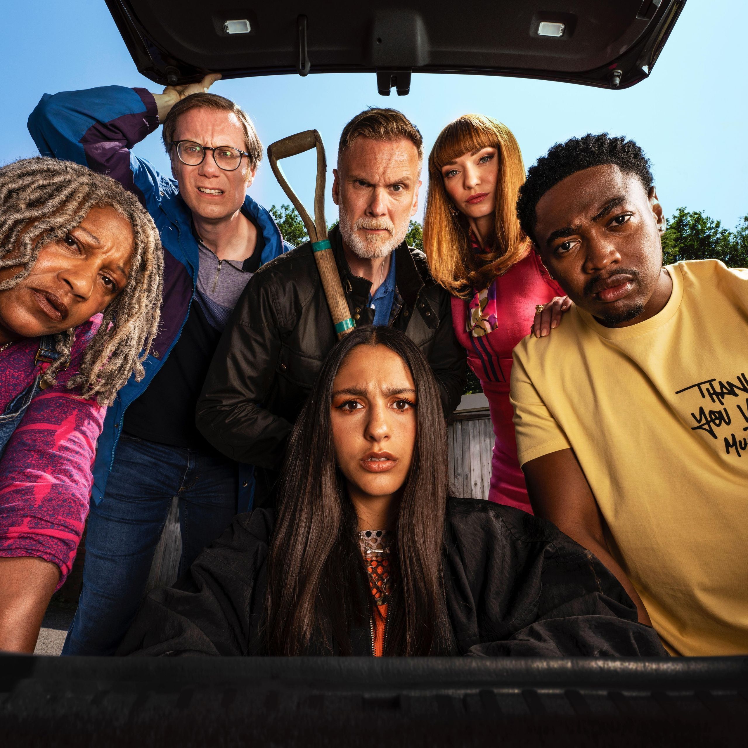 Der gesamte Cast von "The Outlaw" schaut verwirrt in den Kofferraum eines Autos.