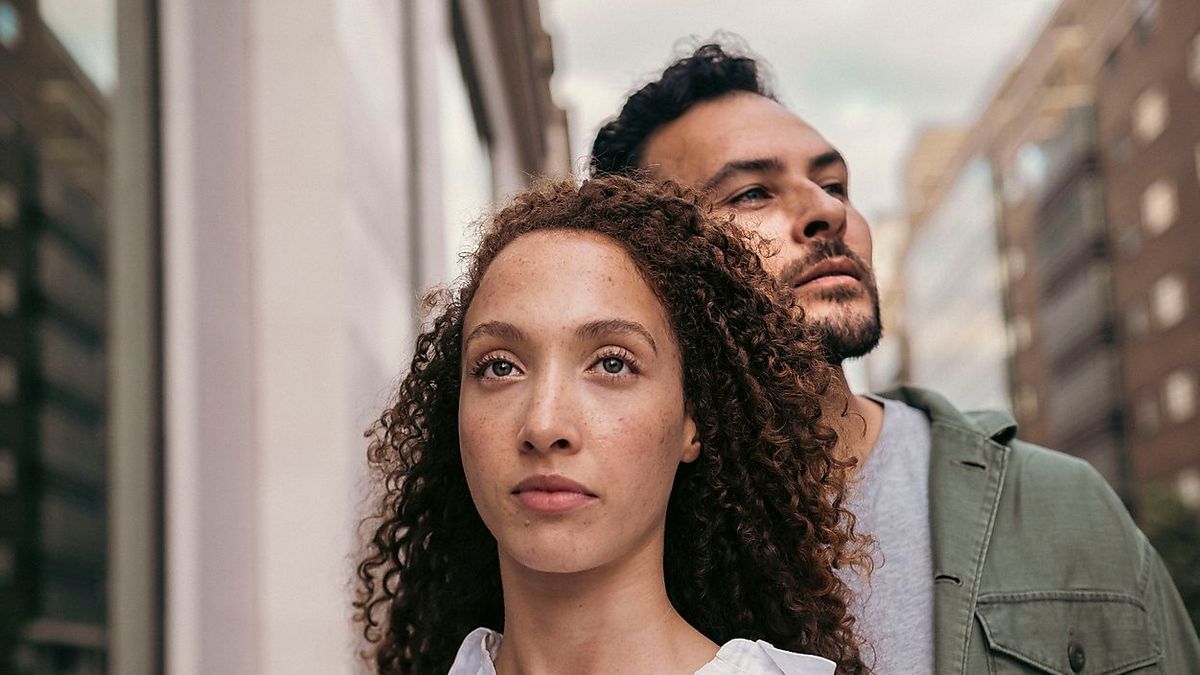 Contemplative woman with curly hair in front of friend