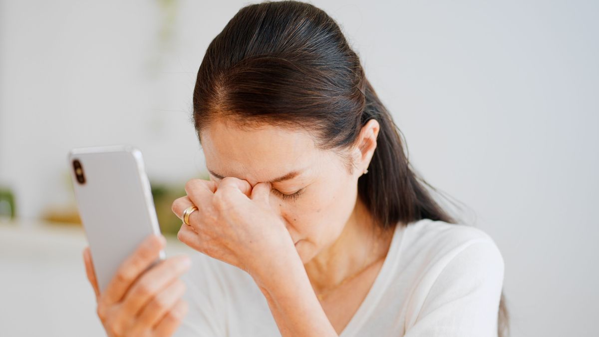 Eine Frau schaut unglücklich und hat ihr Handy in der Hand 