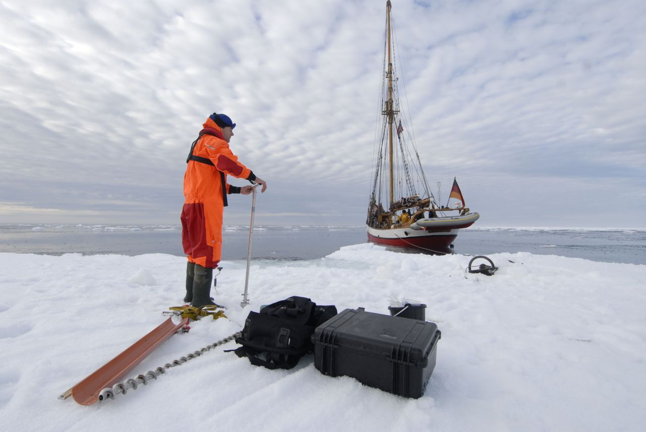 Der Forscher bohrt durchs Meereis und misst die Eisdicke.