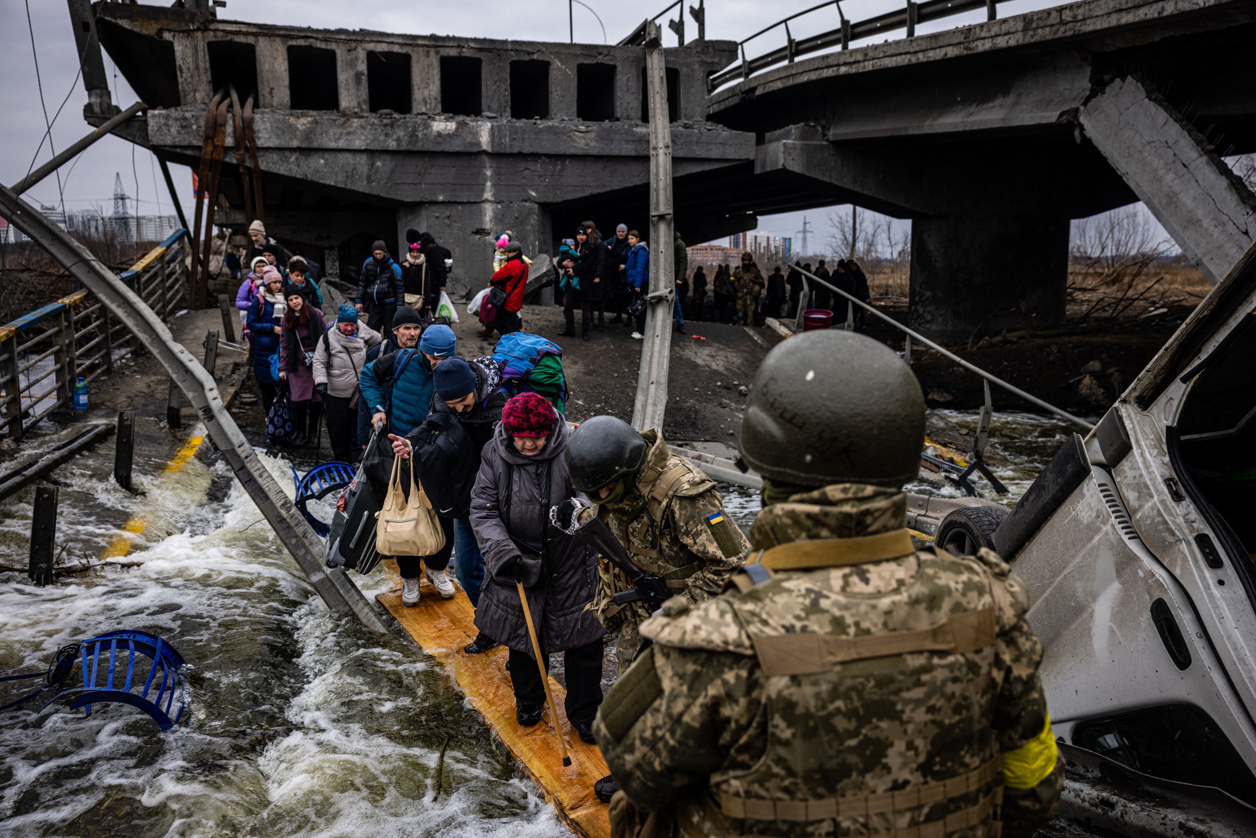 7. März: Ukrainische Kriegsflüchtlinge werden von Soldaten während der Evakuierung über die gesprengte Brücke begleitet. 