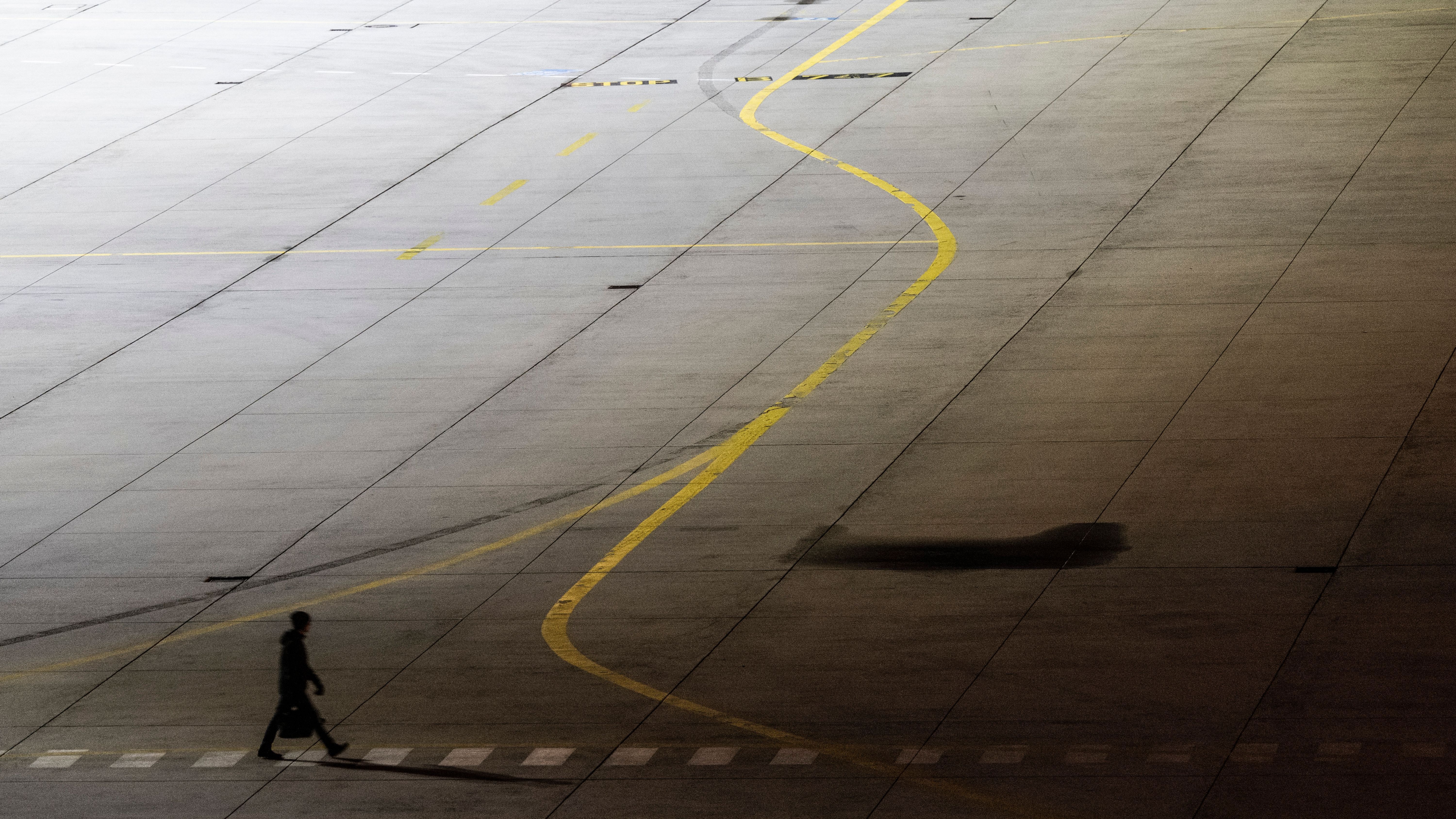 Frankfurt/Main: Ein einzelner Mann geht über das ansonsten leere Vorfeld des Flughafens Frankfurt.