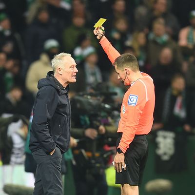 Freiburgs Trainer Christian Streich bekommt von Schiedsrichter Robert Hartmann die Gelbe Karte gezeigt.