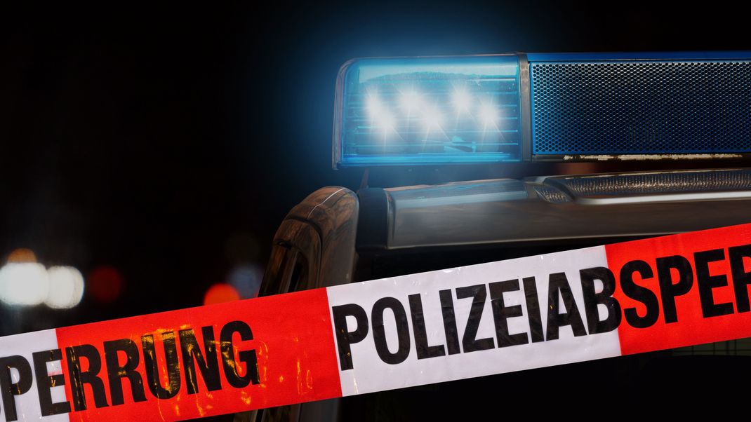 Polizeiabsperrung mit Polizeiauto im Hintergrund bei Nacht