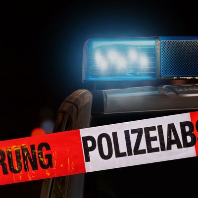 Polizeiabsperrung mit Polizeiauto im Hintergrund bei Nacht