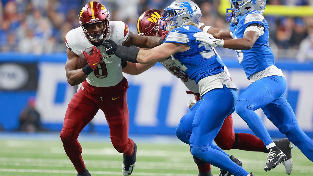 Washington Commanders vs. Detroit Lions DETROIT,MICHIGAN-JANUARY 18: Running back Brian Robinson Jr. (8) of the Washington Commanders carries the ball under the pressure of linebacker Alex Anzalone...