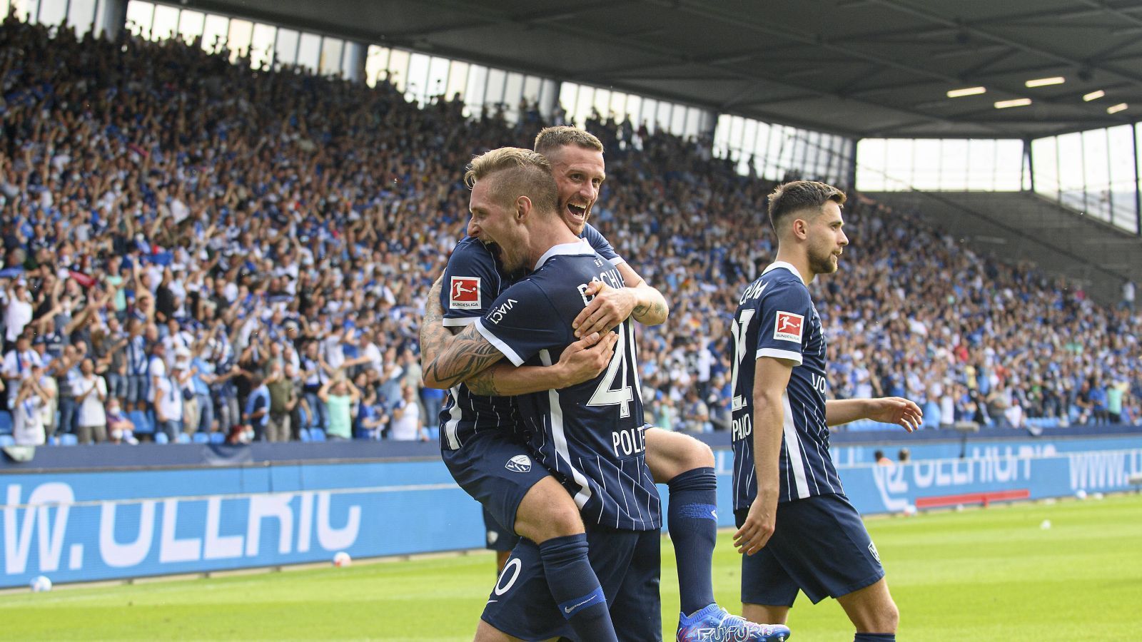 
                <strong>Gewinner: Alle Spieler, Fans und Verantwortliche des VfL Bochum</strong><br>
                Hätte irgendjemand diesen Nachmittag im Vonovia Ruhrstadion besser malen können? Vermutlich nicht. Bei sommerlichen Temperaturen, Sonnenschein und einem ausverkauften Stadion feierte der VfL Bochum an der heimischen Castroper Straße die Rückkehr in die Bundesliga. Dabei mutierte Gerrit Holtmann nicht nur bei seinem traumhaften Solotor zum 1:0 kurz zu Lionel Messi, auch Neu-Angreifer Sebastian Polter feierte mit seinem Premierentreffer einen gelungenen Einstand. Mit diesem Nachmittag kann jeder, der es auch nur entfernt mit dem VfL Bochum hält, zufrieden sein.
              