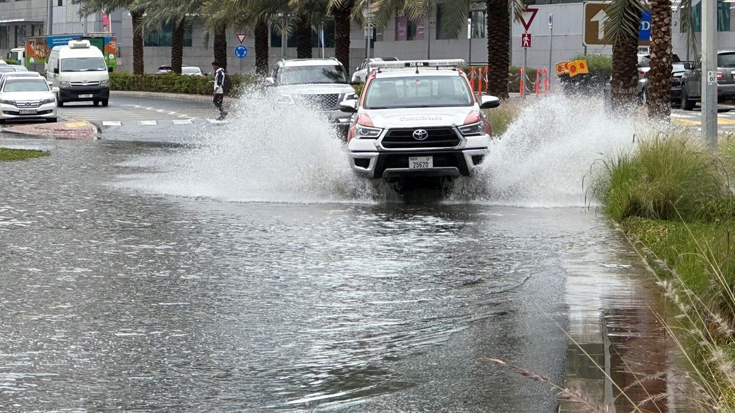 Nach einem heftigen Regensturm fahren Autos durch eine überflutete Straße.