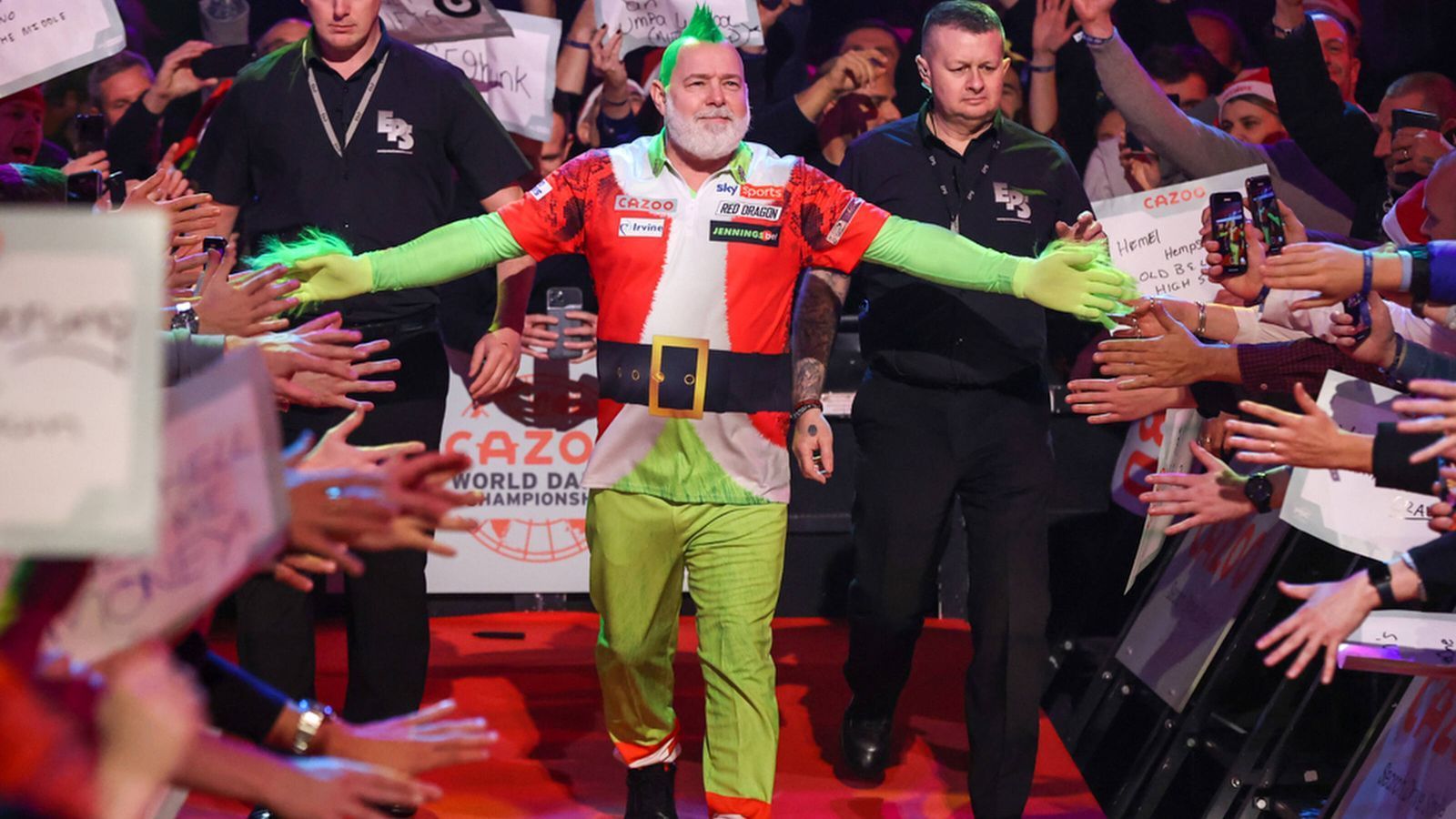 
                <strong>König des Darts und der Kostüme</strong><br>
                Ein Weltmeister muss zum Auftakt der Mission Titelverteidigung als Grinch erscheinen. So will es ein ungeschriebenes Gesetz von Peter Wright. Der 52-Jährige, der ohnehin schon durch seine Irokesen-Frisur und sein Schlangen-Tattoo auf der linken Seite seines Kopfes auffällt, überrascht traditionell bei jedem WM-Spiel mit einem eigens angefertigten Kostüm. Vor allem seine Frau soll beim Designen eine große Rolle spielen. Wie schon bei der WM 2021 erschien Wright zu seiner ersten Pflichtaufgabe am Donnerstagabend als Grinch. Ob er uns wohl allen Weihnachten vermiesen will? 
              