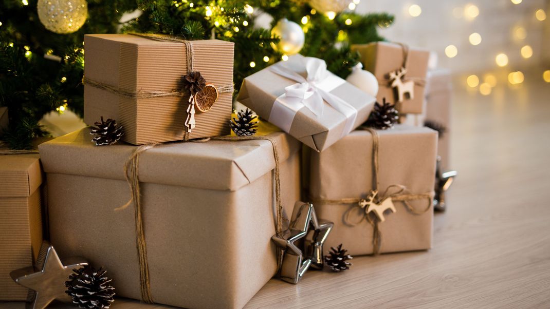 close up of beige gift boxes near decorated christmas tree