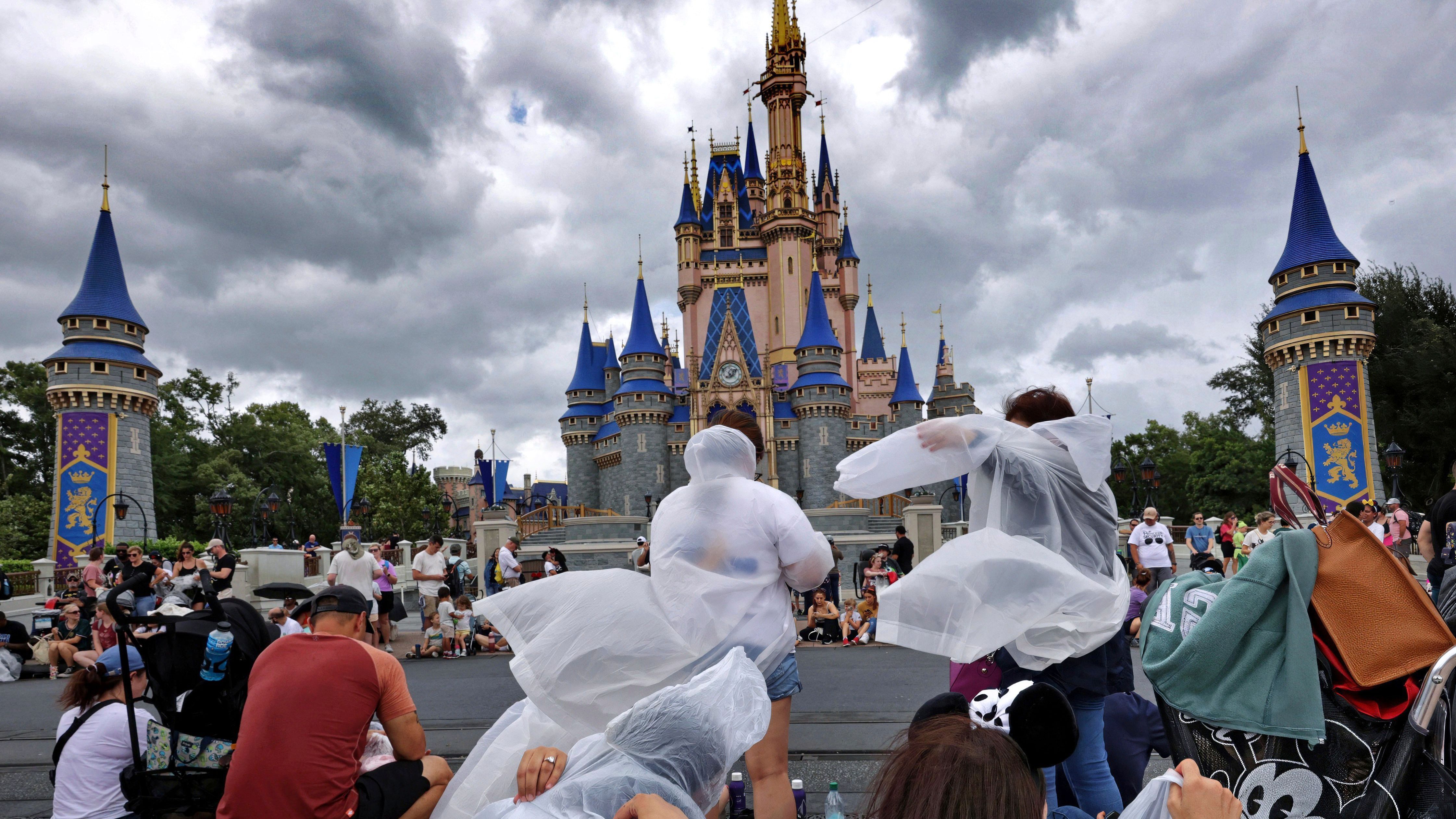 Besucher:innen von Disney Land Florida packen ihre Regenponchos vor dem anstehenden Unwetter aus.