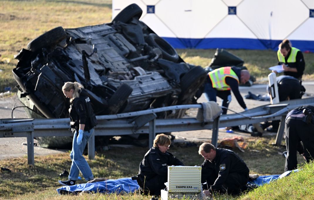 Rettungskräfte und Polizisten stehen am umgestürzten Fahrzeug. Beim Unfall eines mutmaßlichen Schleuserfahrzeugs auf der Autobahn 94 sind sieben Menschen gestorben und mehrere schwer verletzt worden. 