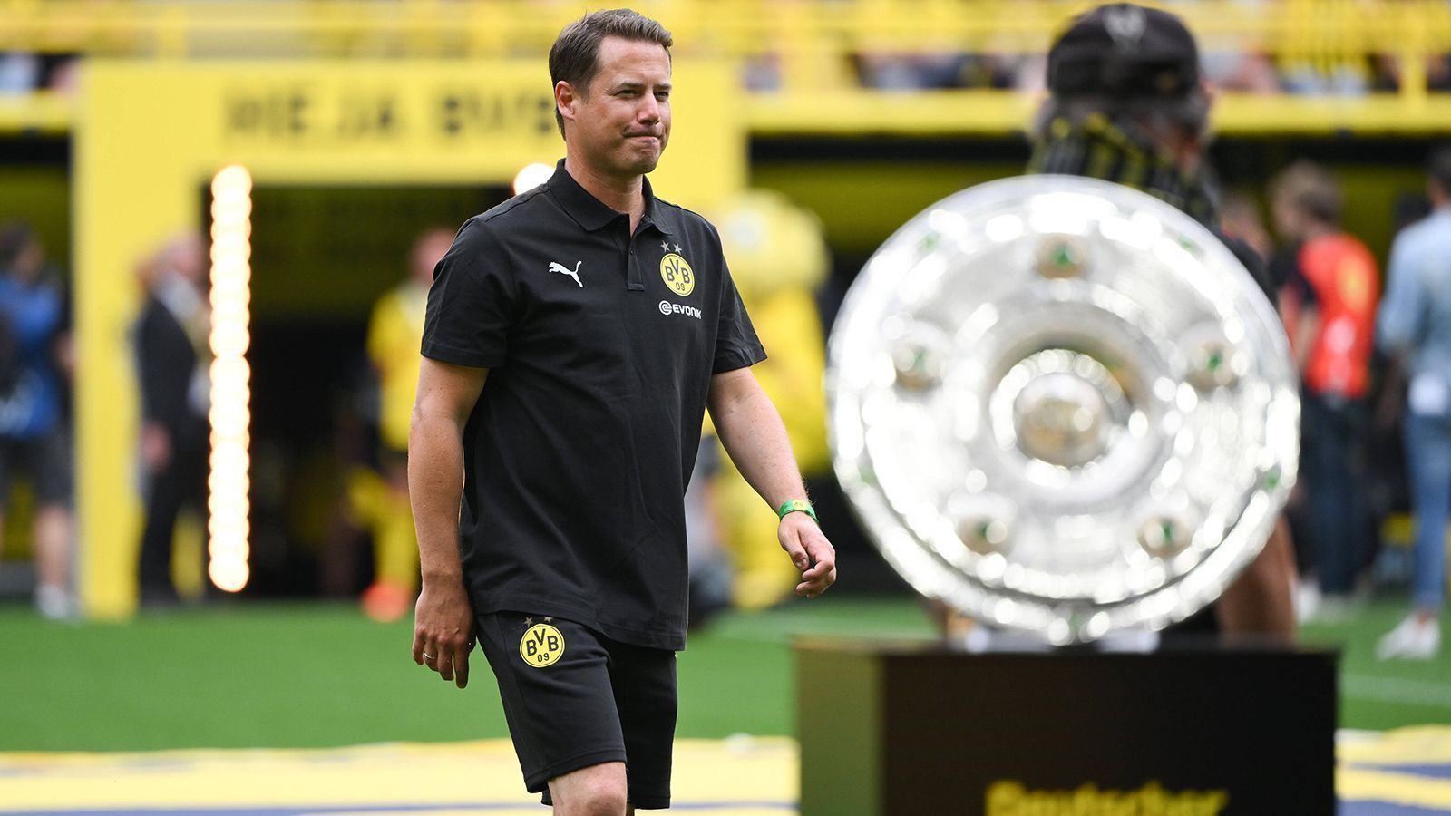 
                <strong>Zentrales Mittelfeld: Lars Ricken</strong><br>
                Lars Ricken? Beim BVB würde man ihn mit dem Wort Legende beschreiben - und er hat nicht ohne Grund diesen Status. Schon in der Jugend kickte er für die Borussia und spielte sich durch die Nachwuchsmannschaften in die A-Mannschaft hoch. Für diese kam er in der Bundesliga auf 301 Einsätze. Zu seinen größten Erfolgen zählen der Weltpokalsieg 1997 und der Champions-League-Sieg im gleichen Jahr. Sein Tor im Finale gegen Juventus Turin ist bis heute legendär. Nun ist der 46-Jährige als Nachwuchskoordinator im Verein aktiv und dort bis Sommer 2025 gebunden. 
              