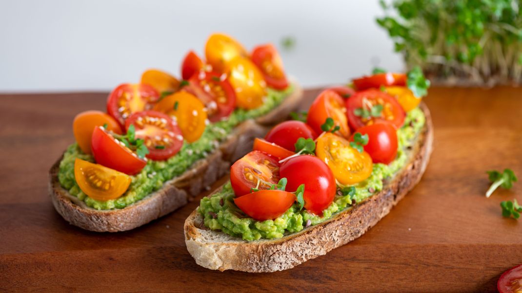 Der perfekte Snack: Knuspriges Brot mit Avocado- und Tomaten-Topping.