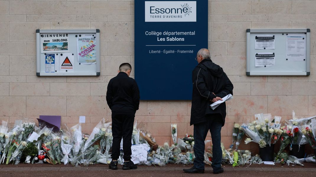 Anwohner betrachten die Blumen, die nach dem gewaltsamen Tod eines 15-Jährigen vor dem Eingang der Mittelschule Les Sablons in Viry-Châtillon niedergelegt worden sind.