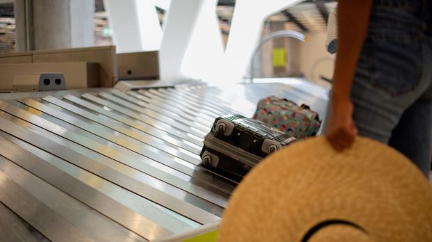 Frau wartet auf ihr Reisegepäck am Flughafen
