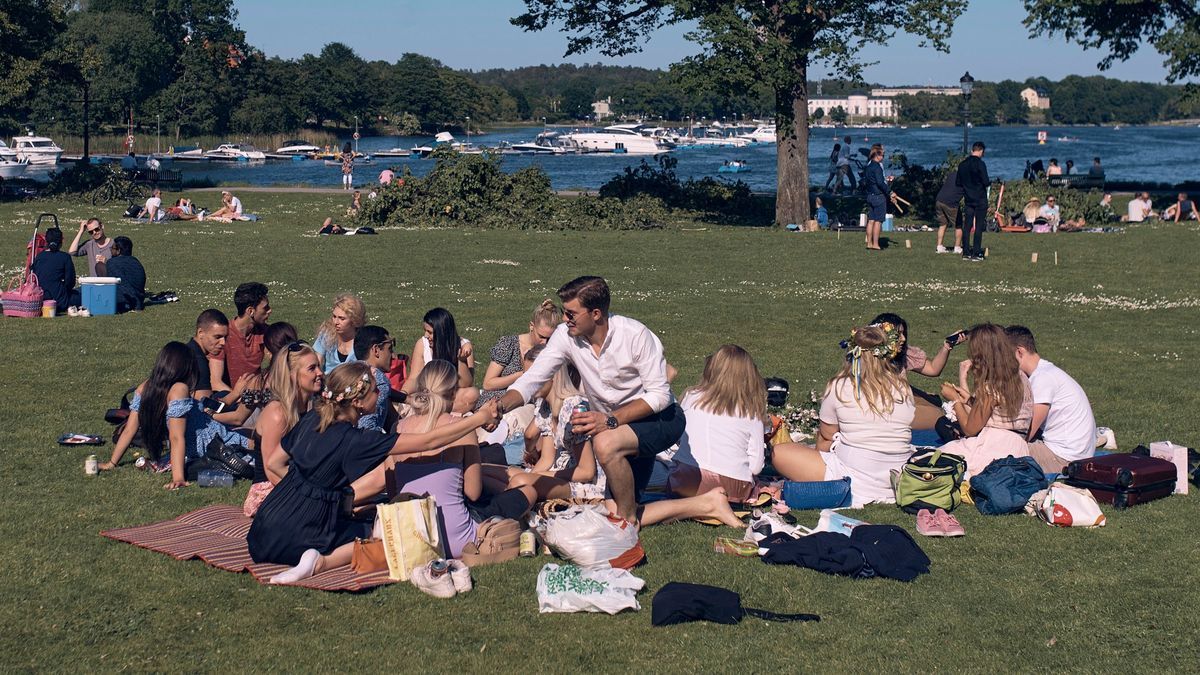 Schweden, Stockholm: Eine Gruppe junger Menschen picknickt während der jährlichen Mittsommer-Feierlichkeiten. In Skandinavien wird zur Sommersonnenwende das Mittsommer-Fest gefeiert.