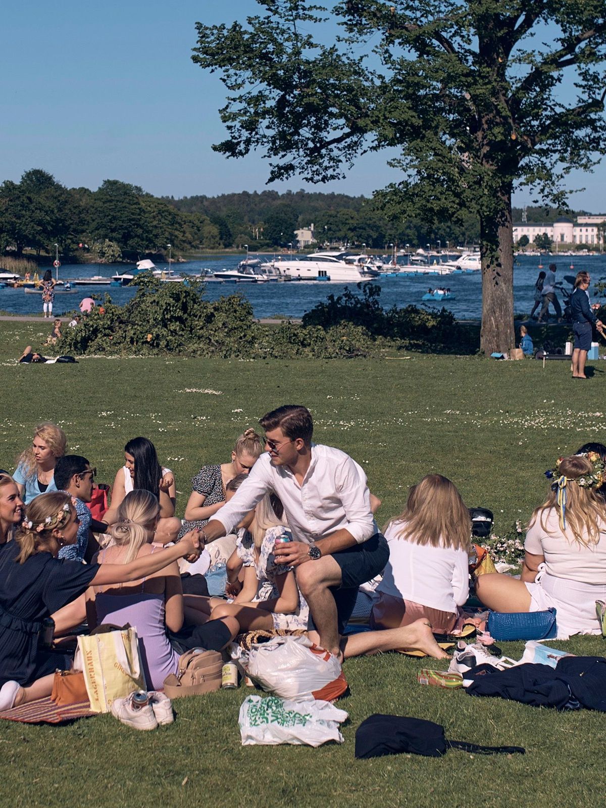 Schweden, Stockholm: Eine Gruppe junger Menschen picknickt während der jährlichen Mittsommer-Feierlichkeiten. In Skandinavien wird zur Sommersonnenwende das Mittsommer-Fest gefeiert.